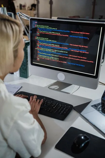 Dual monitors on a desk, showcasing web design in a modern office setting.
