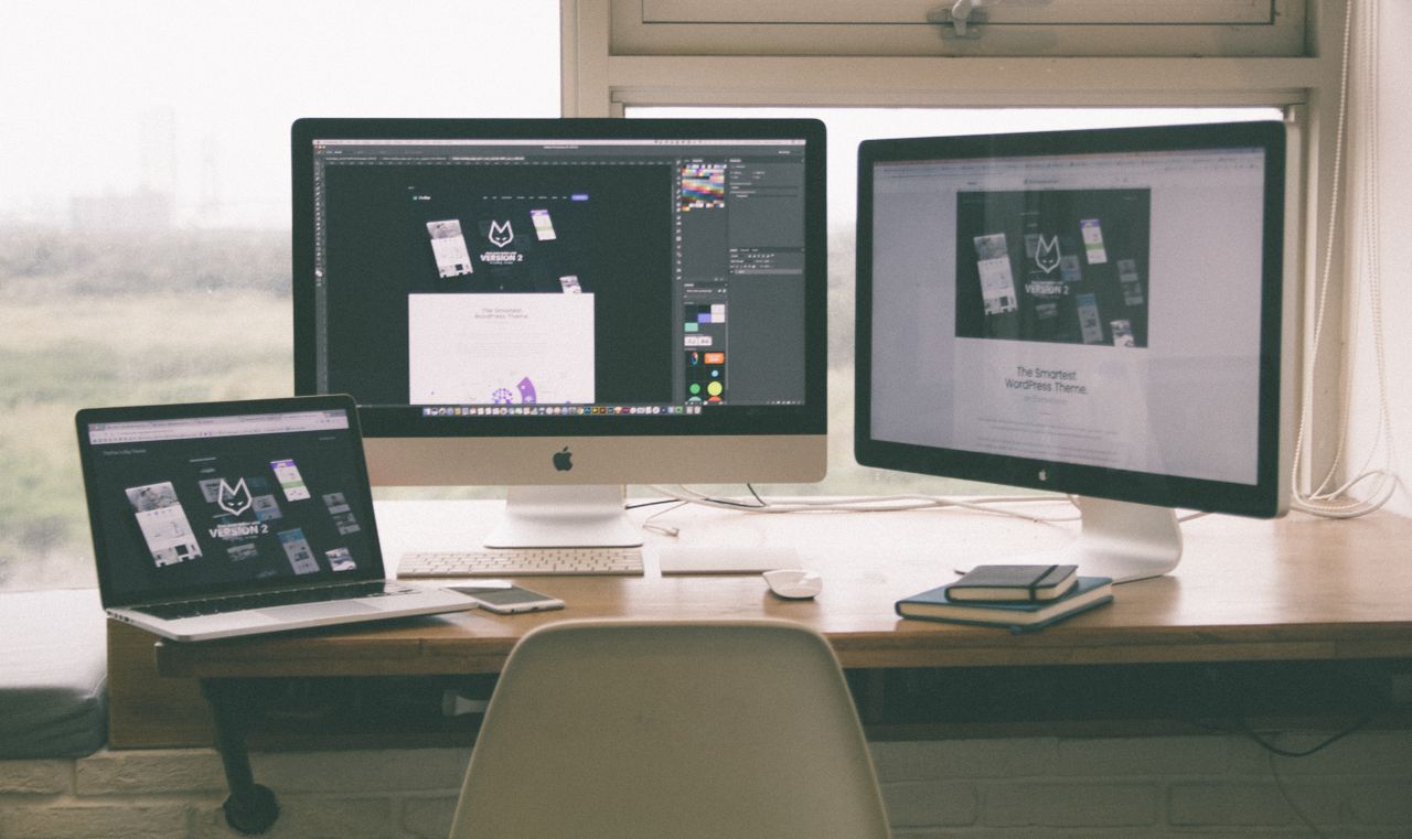 Workspace élégant et performant avec plusieurs écrans, un ordinateur portable et un smartphone, mettant en avant un projet de web design.